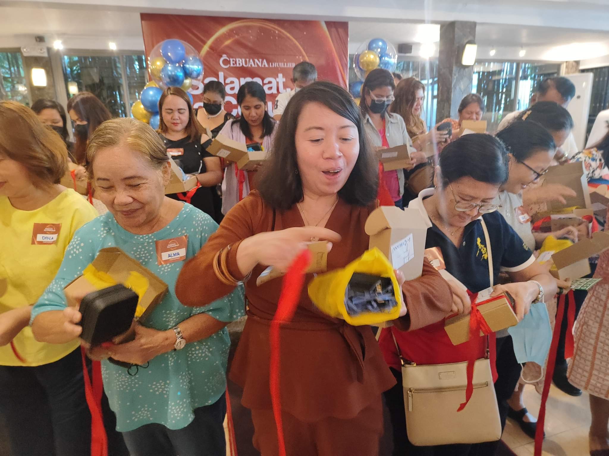 Ana Marie Mendoza Rapido (center), a public-school teacher was overcame with emotions while opening her special surprise gift from Cebuana Lhuillier 